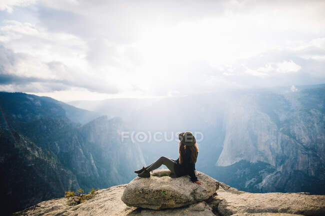 Young woman sitting at top of mountain, overlooking Yosemite National Park, California, USA — Stock Photo