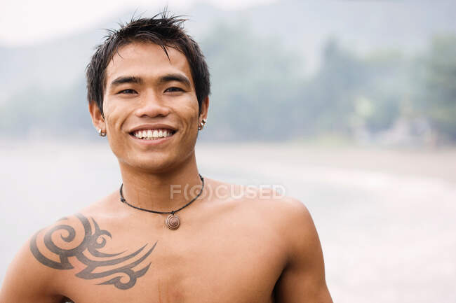 Ragazzo con tatuaggio sorridente alla macchina fotografica — Foto stock