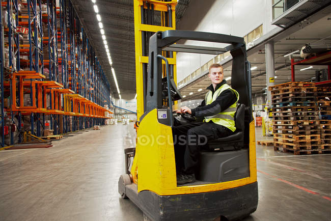 Worker operating forklift in warehouse — Stock Photo