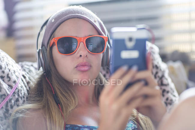 Teenager with sun glasses using smartphone on lazy chair — Stock Photo