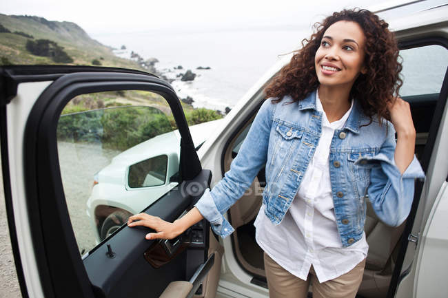 Giovane donna che scende dalla macchina sulla costa — Foto stock