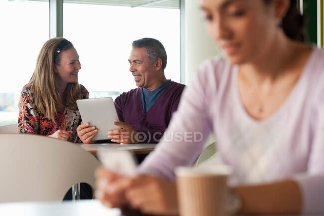 Homem usando tablet digital, mulher mensagens de texto em primeiro plano — Fotografia de Stock