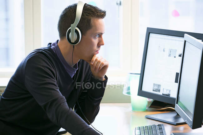 Uomo che usa i computer alla scrivania — Foto stock