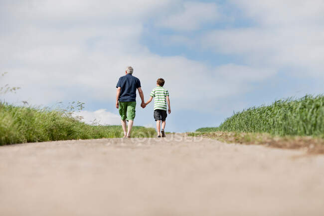 Father and son walking up a road — Stock Photo