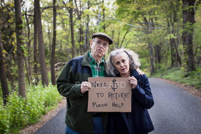 Senior couple holding sign in forest, portrait — Stock Photo
