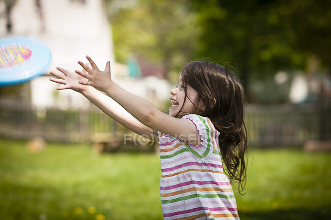 Giovane ragazza che lancia frisbee in giardino — Foto stock