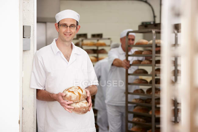 Chef sosteniendo panes en la cocina - foto de stock