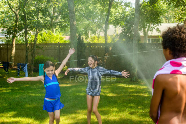 Trois enfants jouent au jardin avec tuyau d'arrosage — Photo de stock