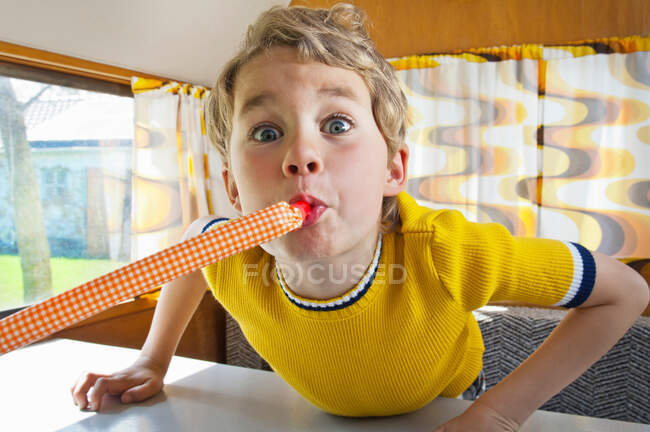 Boy blowing party blower in caravan — Stock Photo