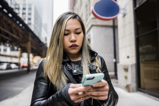 Mujer joven, al aire libre, usando teléfono inteligente - foto de stock