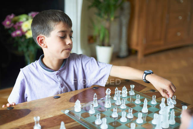 Хлопчик грає в шахи у вітальні — стокове фото