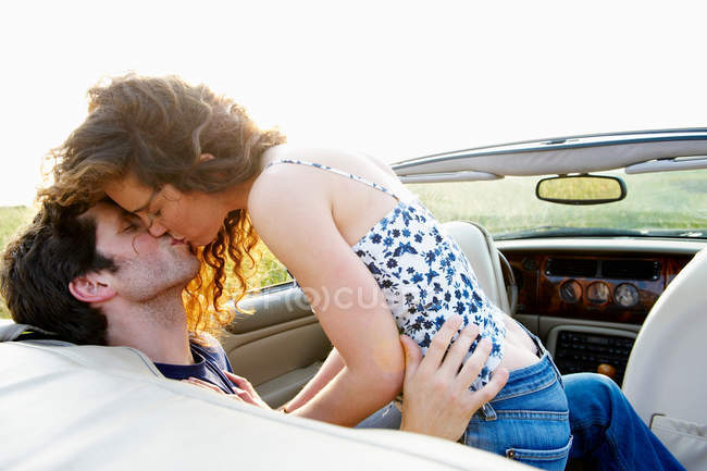 Pareja besándose en un convertible - foto de stock