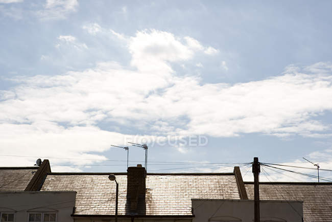 Дахи будинків і блакитне хмарне небо — стокове фото