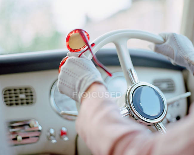 Mãos femininas em luvas com óculos de sol no volante — Fotografia de Stock