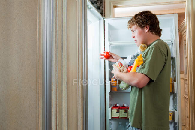 Хлопчик-підліток бере їжу з холодильника — стокове фото