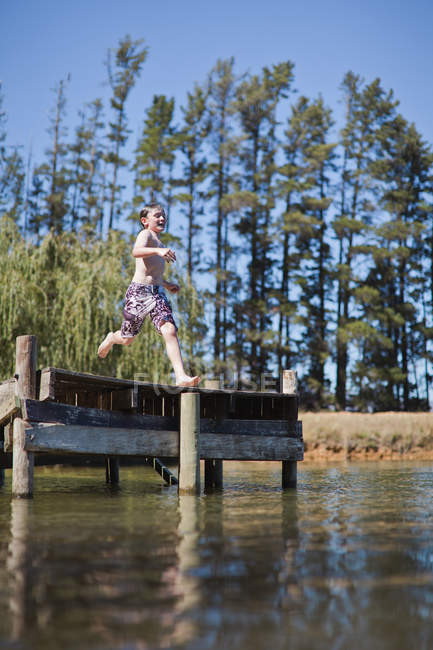 Rapaz saltando para o lago a partir de molhe — Fotografia de Stock