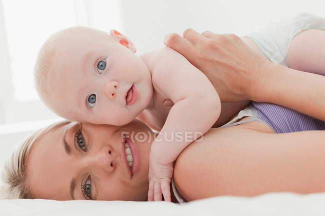 Madre abrazando bebé en la cama - foto de stock