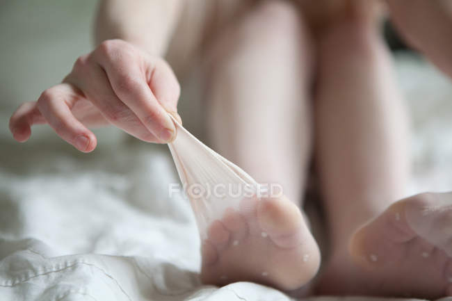 Mulher puxando meias longe de seus dedos dos pés — Fotografia de Stock