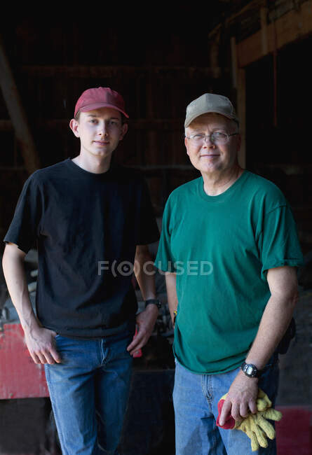 Зрелый фермер и сын в сарае, портрет — стоковое фото