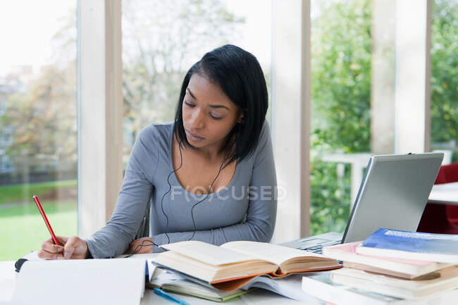 Estudiante universitario escribiendo en el escritorio - foto de stock