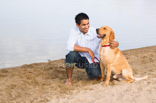 Uomo e golden retriever in spiaggia — Foto stock