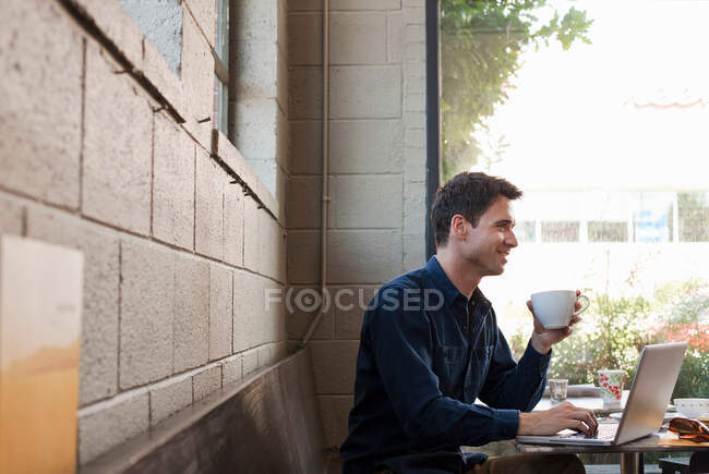 Empresario usando laptop en cafetería - foto de stock