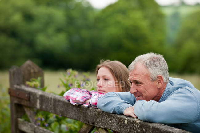 Отец и дочь на деревянном заборе — стоковое фото