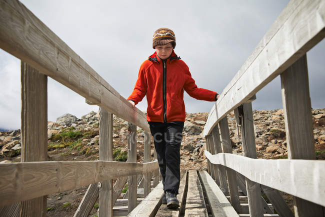Ragazza che cammina sul ponte pedonale in legno — Foto stock
