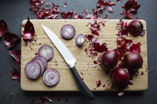 Cebollas rojas frescas en rodajas en la tabla de cortar - foto de stock