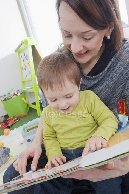 Madre che legge a figlio a casa — Foto stock