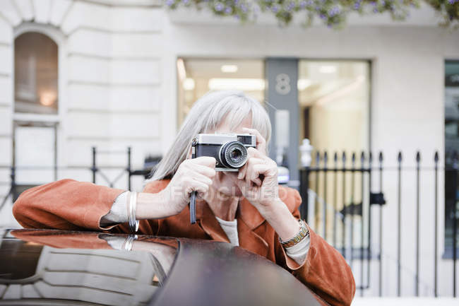 Woman taking picture on city street — Stock Photo