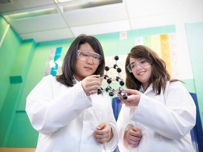Estudiantes de ciencias que estudian modelo molecular en laboratorio escolar - foto de stock