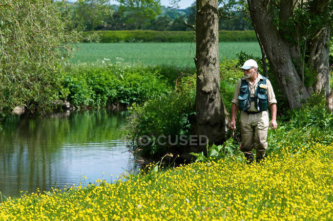 Fisherman walking along river — Stock Photo