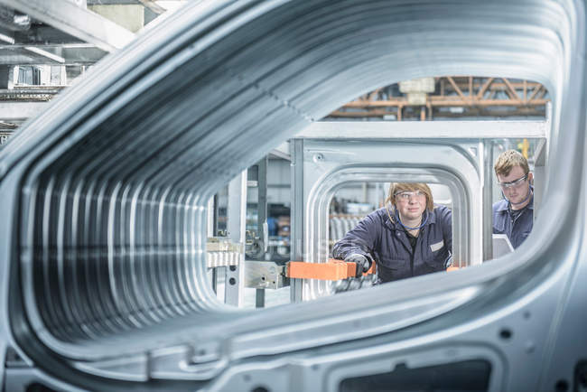 Apprentices inspecting section of car body in car plant — Stock Photo