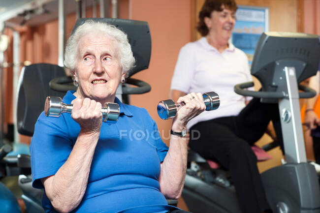 Donna anziana che solleva pesi in palestra — Foto stock