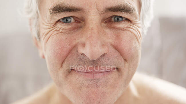 Hombre mayor sonriendo y mirando a la cámara - foto de stock