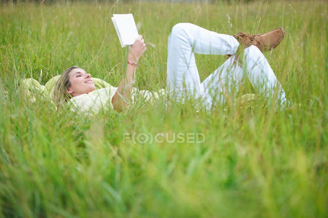 Mulher lendo na grama alta — Fotografia de Stock