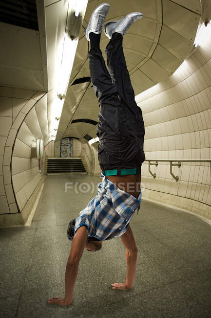 Un hombre haciendo una parada de manos en el metro - foto de stock