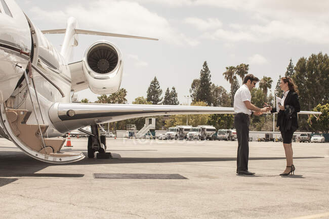 Donna d'affari stringendo la mano con pilota jet privato in aeroporto — Foto stock