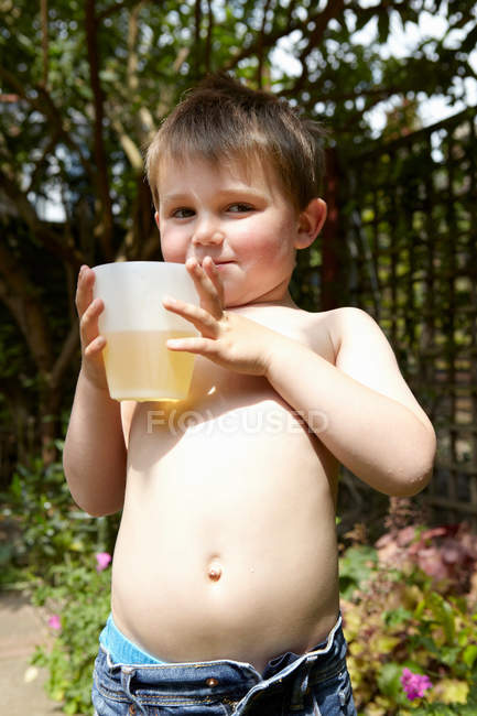 Хлопчик п'є сік в саду — стокове фото