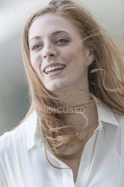 Portrait of beautiful young woman with long red windswept hair — Stock Photo