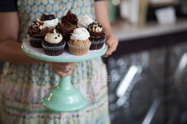 Bäckereibesitzer trägt Tablett mit allergikerfreundlichen Cupcakes — Stockfoto