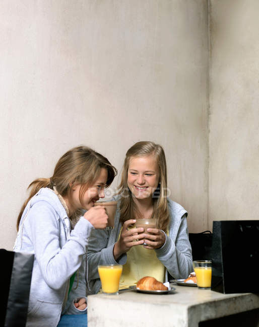 Две улыбающиеся девушки пьют кофе — стоковое фото