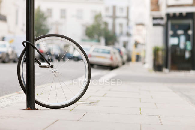 Single bicycle wheel secured to lamp post — Stock Photo