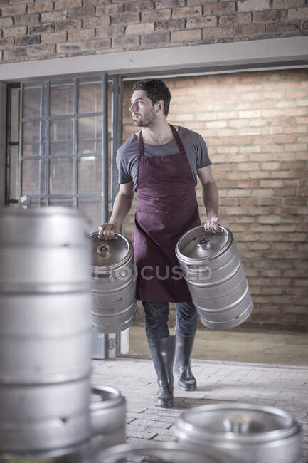 Brewer carrying two kegs of beer — Stock Photo