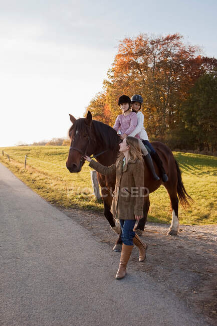 Mulher andando um cavalo com duas meninas — Fotografia de Stock