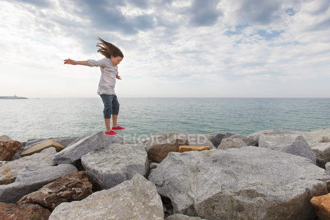 Mädchen spielt am Strand auf Felsen — Stockfoto