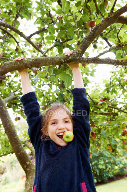 Sonriente chica jugando en árbol frutal - foto de stock