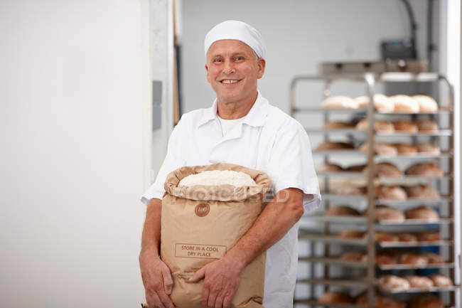 Chef llevando saco de harina en la cocina - foto de stock