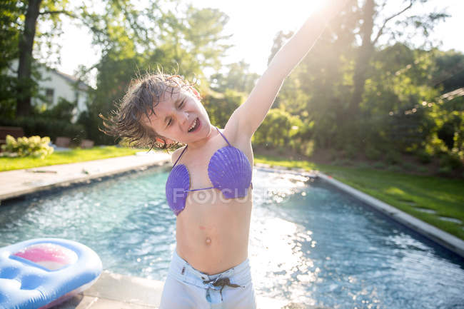 Boy in seashell biquíni top dançando por piscina exterior — Fotografia de Stock